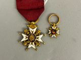 deux médailles d'or et un ruban rouge sur un fond blanc