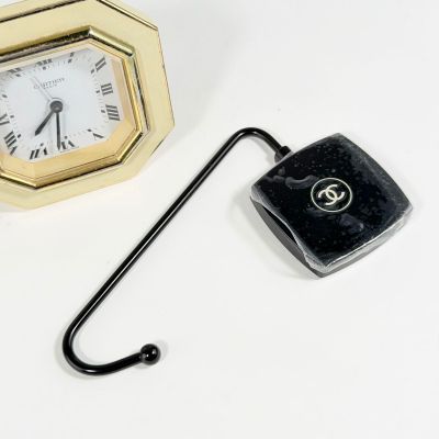 une petite horloge et un crochet posés sur une table blanche