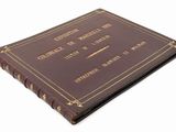 an old brown book with gold writing on it sitting on top of a white surface
