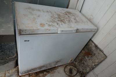 a dirty refrigerator in the corner of a dirty room