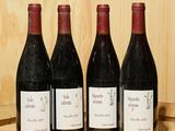 quatre bouteilles de vin sont alignées sur un tonneau en bois