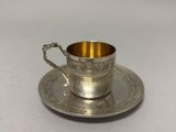 a silver cup and saucer on a saucer on a white surface