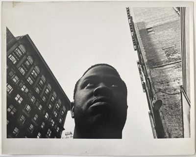 photographie en noir et blanc d'un homme debout devant un grand immeuble