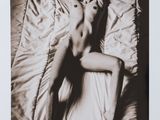 black and white photograph of a naked woman laying on a bed