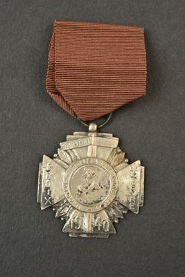 une vieille médaille entourée d'un ruban, posée sur une surface noire