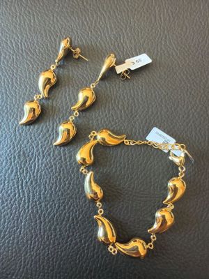 a pair of gold tone bracelets and earrings on a black leather surface
