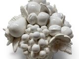 a white vase with a bunch of fruit on top of it