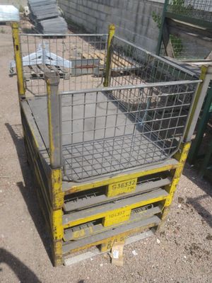 une cage métallique posée sur une palette, dans la terre