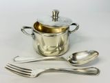 a silver pot and two spoons next to each other