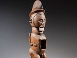 une statue en bois d'une femme avec un chapeau sur la tête