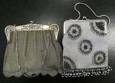 two silver purses sitting on top of a table next to each other