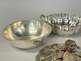 two silver dishes and a silver bowl on a white surface