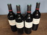 four bottles of wine are lined up on a wooden table