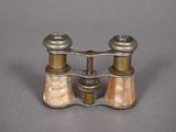 pair of antique brass and mother of pearl binoculars on grey background