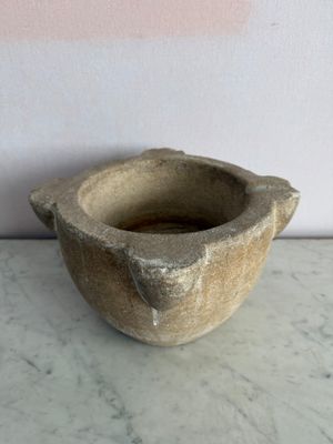 un petit bol en pierre posé sur une table en marbre