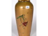 un vase doré sur lequel est peinte une fleur rouge