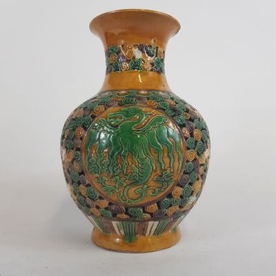 un vase vert et jaune posé sur une surface blanche