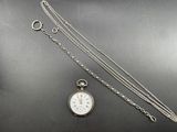 an image of a silver pocket watch and chain on a table