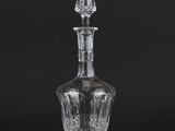a clear glass decanter with a stopper on a black background