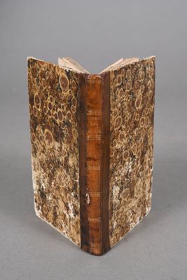 an old book with a brown cover sitting on top of a table