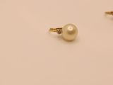 a pair of pearl and diamond earrings on a white surface