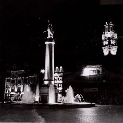une photo en noir et blanc représentant une fontaine et une tour horloge