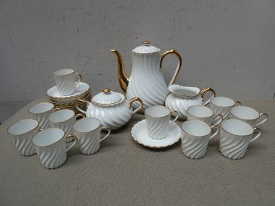 une photo d'un service à thé blanc et doré, avec des tasses et des soucoupes