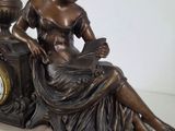 a bronze statue of a woman sitting on a clock