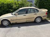 beige car parked on the side of the road in front of a hedge