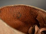 a close up of a brown leather boot with a hole in it
