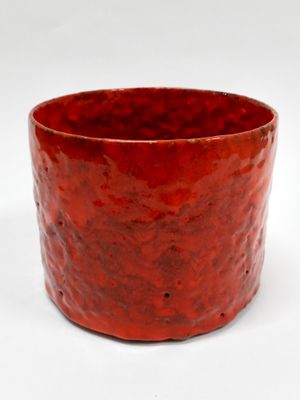 un gobelet rouge posé sur une surface blanche