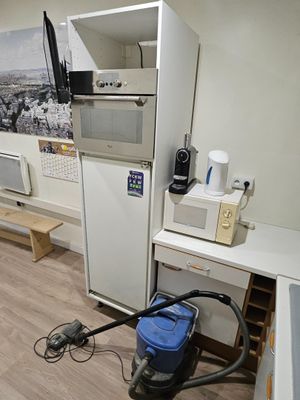 une petite cuisine équipée d'un réfrigérateur, d'un micro-ondes et d'autres appareils électroménagers