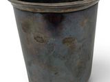 a metal cup that is sitting on a white surface
