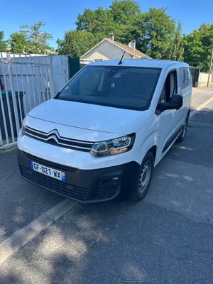 une camionnette blanche garée sur un parking près d'une clôture
