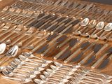 de nombreuses cuillères et fourchettes en argent posées sur une table en bois
