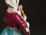 a figurine of a woman in a blue dress holding a carrot