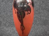an orange vase with a black design on it