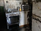 a dirty kitchen with a stove, microwave, and refrigerator