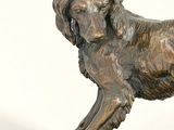 bronze statue of a dog on a rock on a white background