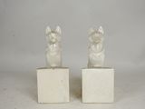 pair of white ceramic dog figurines on marble bases