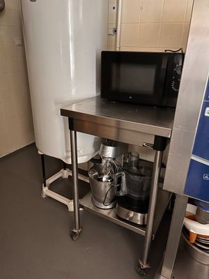 a small kitchen with a microwave on a metal stand