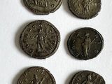 six ancient roman coins are shown in a row on a white surface