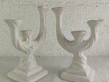 two white vases sitting on a table with a white wall in the background