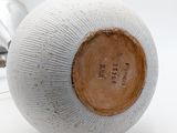 a white vase with a brown lid on a white table