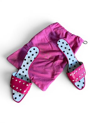 des chaussons à pois roses et blancs et un sac rose posés sur une surface blanche