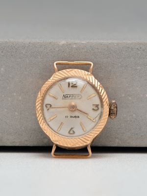 a gold watch with a white face sitting on top of a table