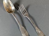 two silver spoons and a fork on a table