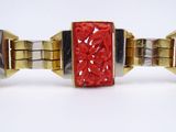a gold bracelet with a red stone in the middle