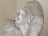 une sculpture en pierre représentant un homme coiffé d'une coiffe, posée sur une table