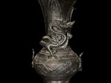 a silver vase with a dragon on it on a black background